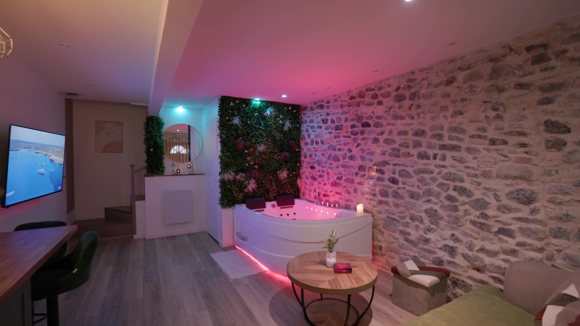 Salon de la love room avec jacuzzi privatif, mur végétal et pierres apparentes